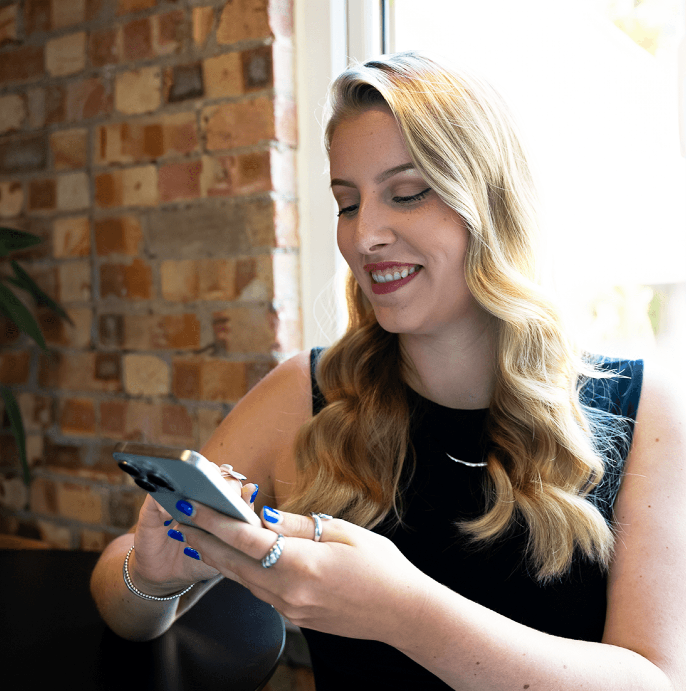 Smiling blonde female on her phone using a telephone answering app.