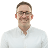 Portrait of caucasian male with glasses smiling at the camera wearing a shirt.