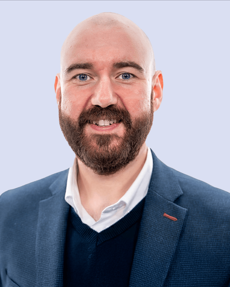 Portrait of a male with a beard wearing a navy blazer and a white shirt